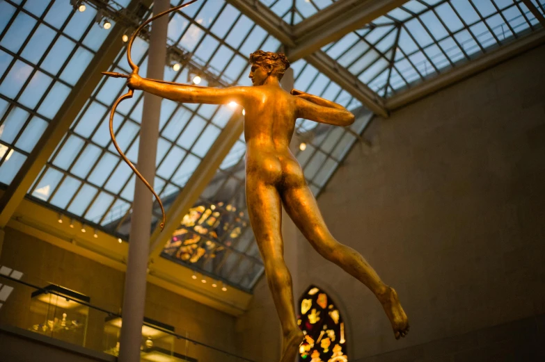 a bronze statue standing in the center of a room with large glass windows