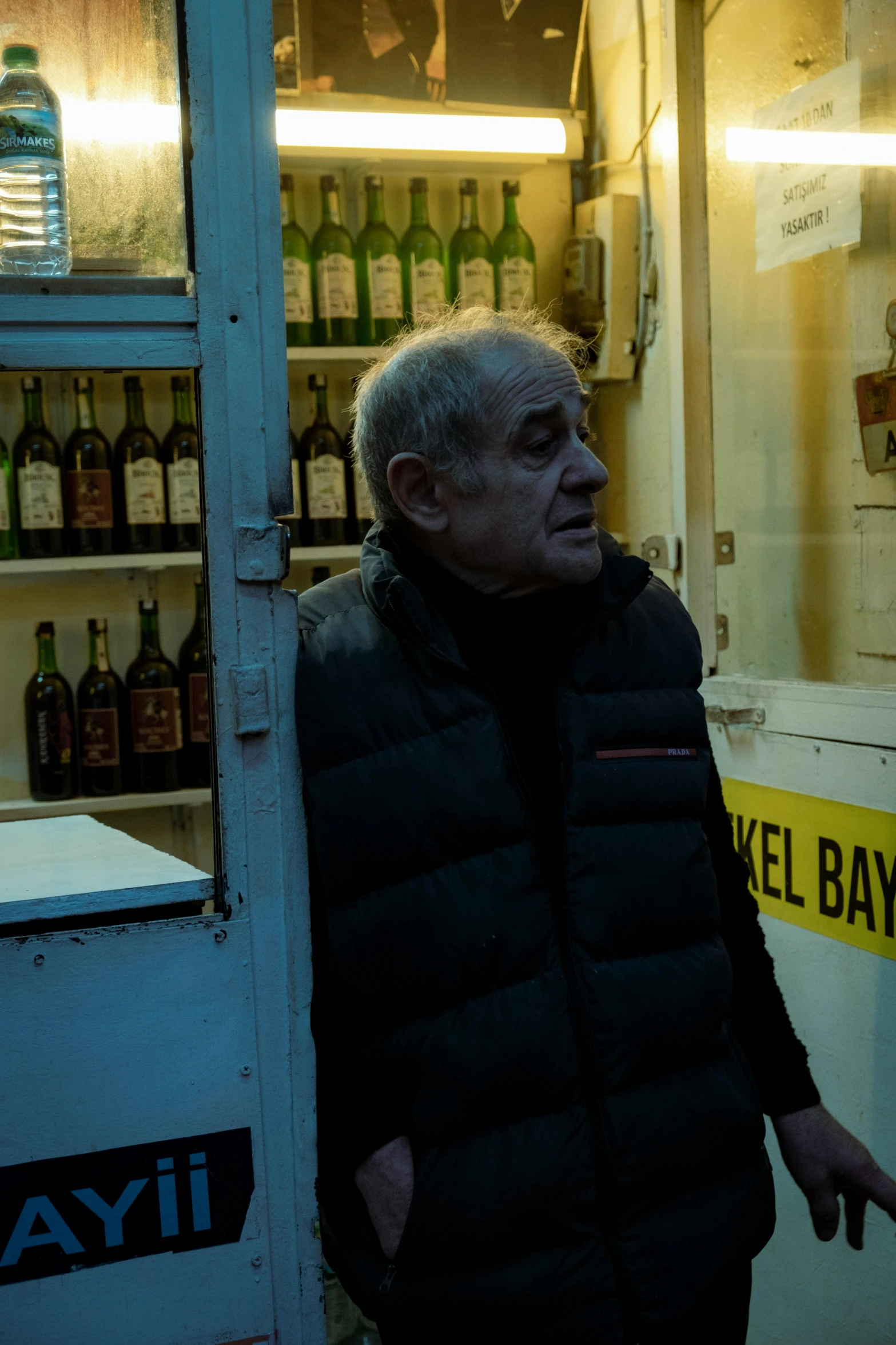 a man standing outside an open refrigerator and next to shelves of beer