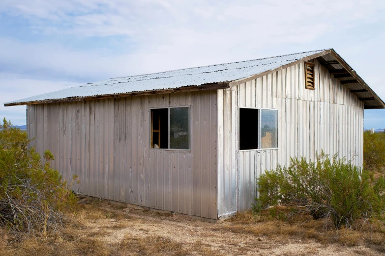 the building is made out of boards and is sitting alone in the dirt