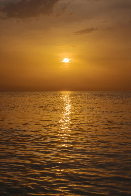 sun setting in the ocean, with small ripples in the water