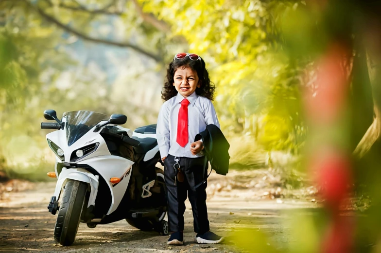 a small child in dress clothes standing next to a motor bike