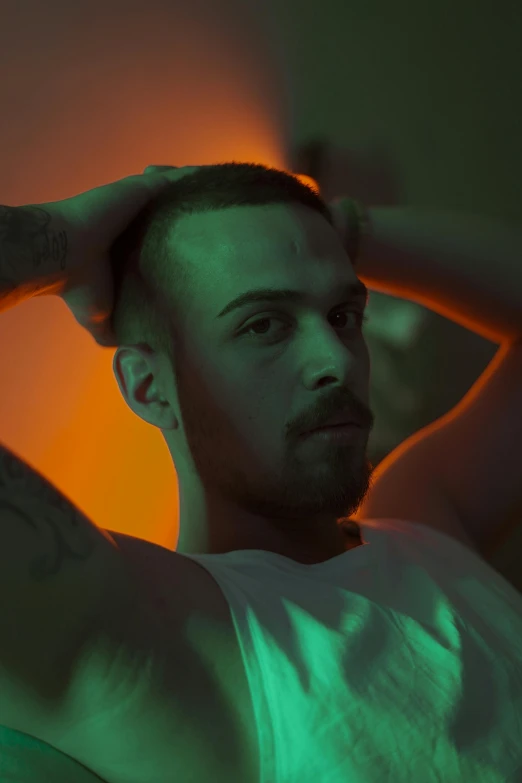 a man standing in a dark room with a tattooed hand on his head