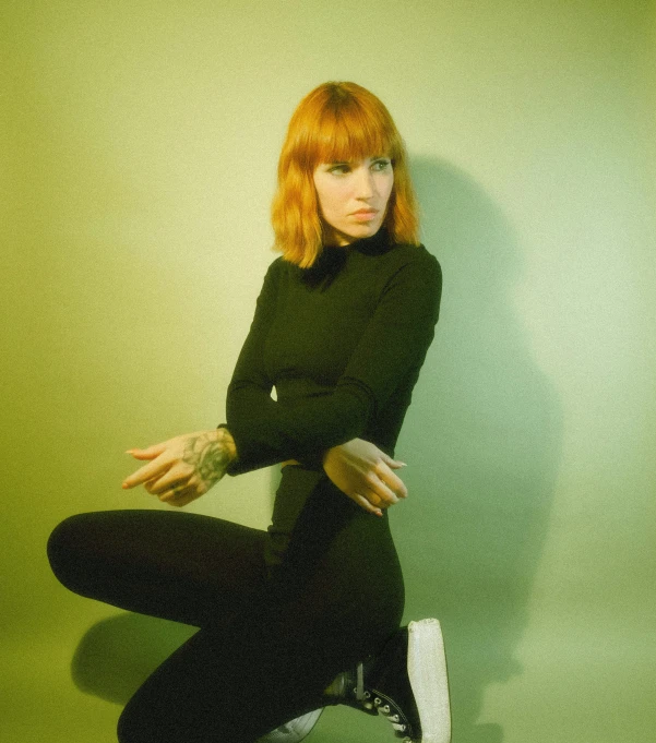 woman sitting down in front of a green wall