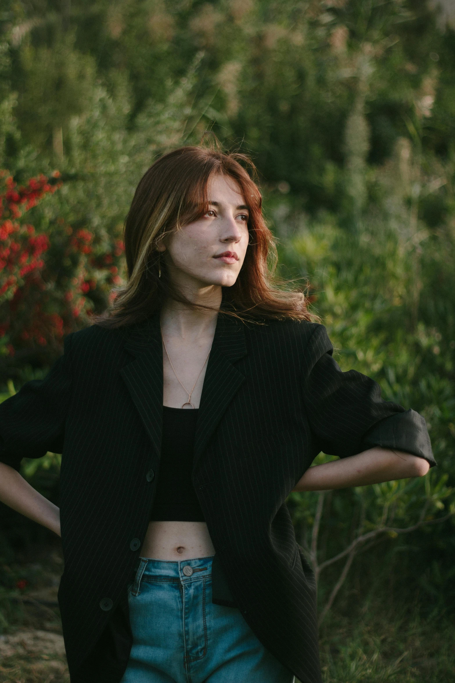 a woman posing in the grass by some flowers