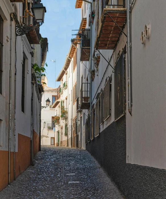 the view from down a narrow street that is lined with white houses