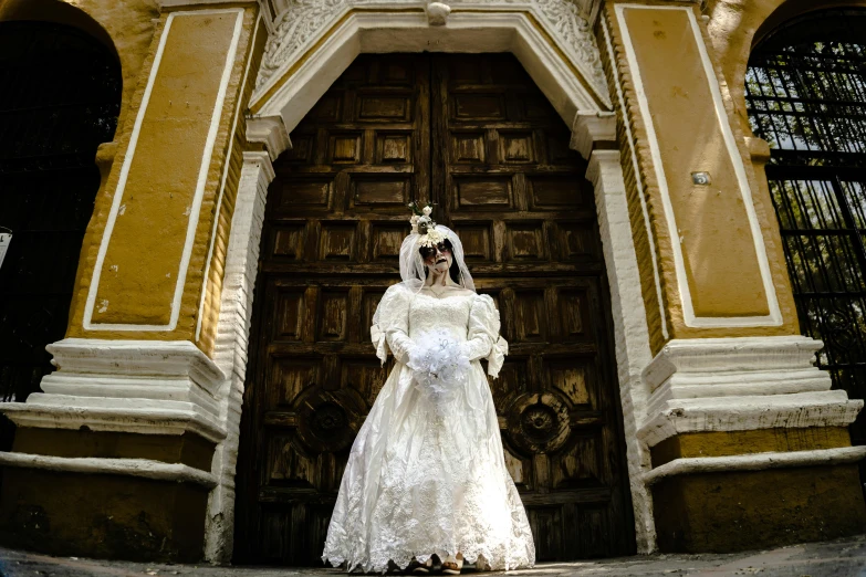 a woman in a bridal dress stands in front of an ornately decorated doorway