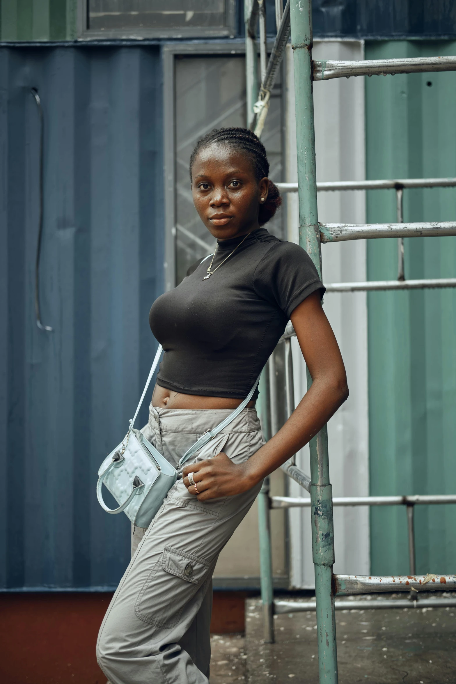 a young woman in grey pants holding a white purse