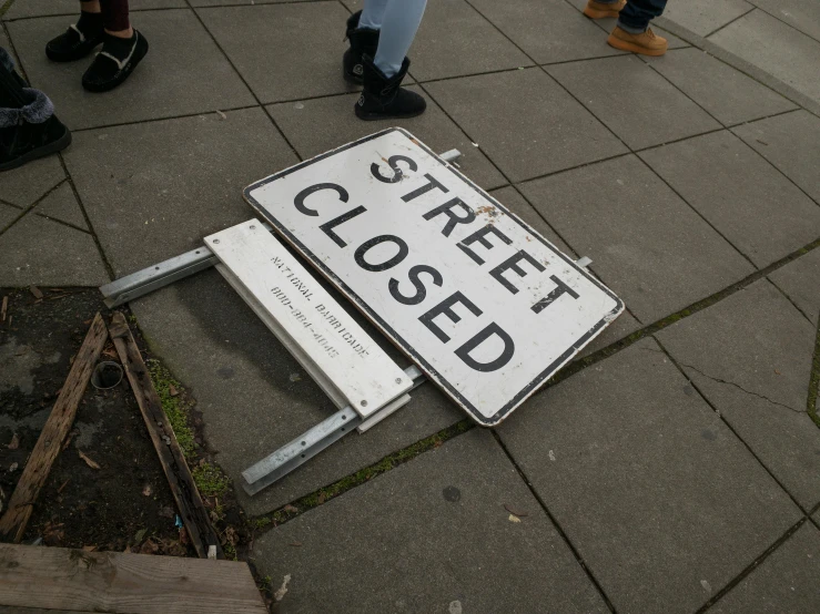 there is a closed street sign that is on the side walk