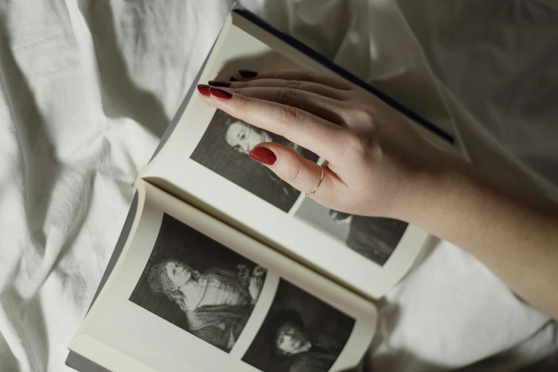 a person with nail polish holds a po book