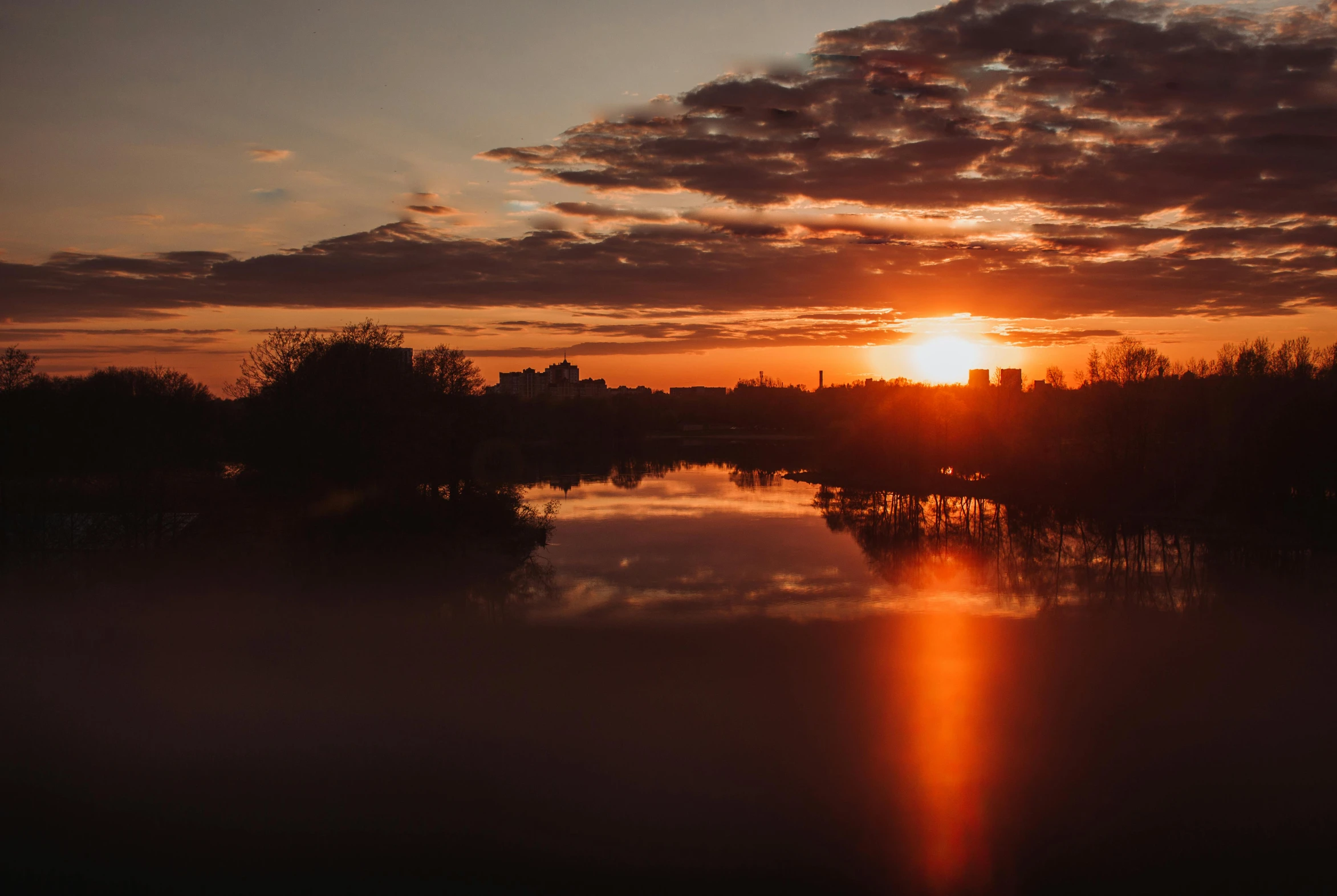 the sun sets on a river and there is still water