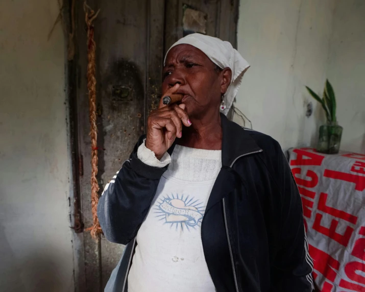 an older woman smoking a cigarette near a doorway