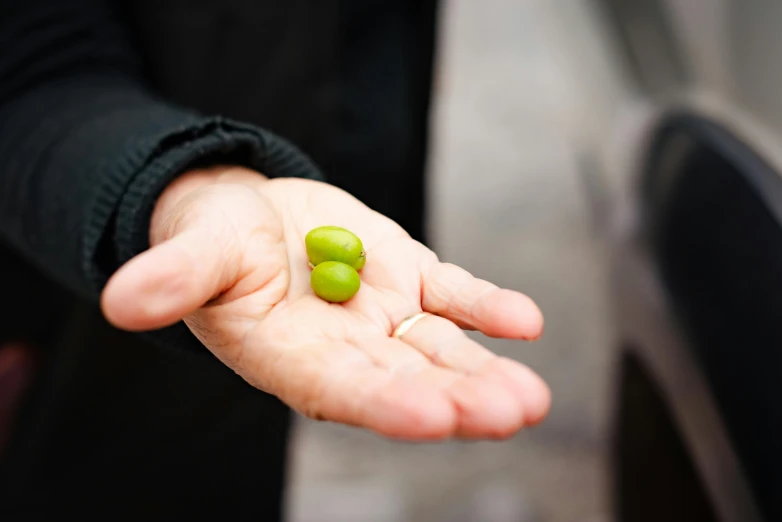 someone holding a green piece of peas in their palm