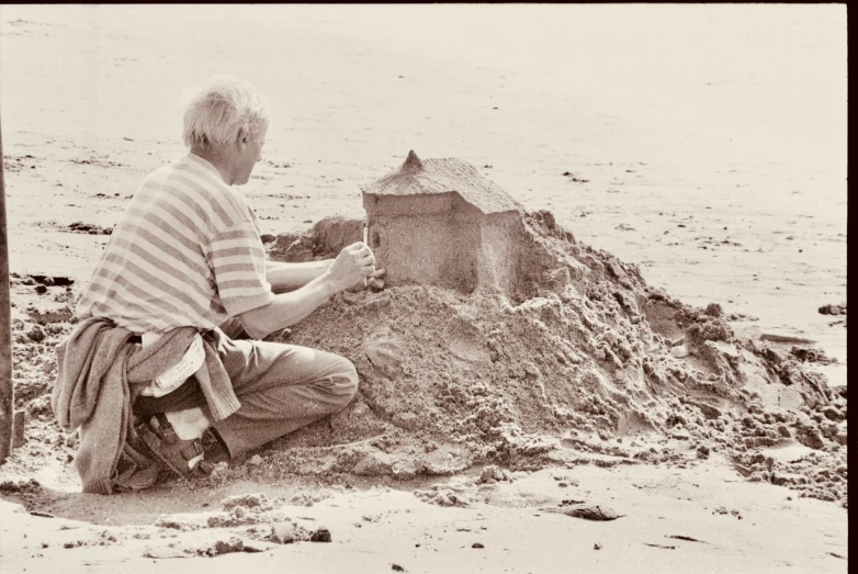 an old man sitting on the beach near some sand