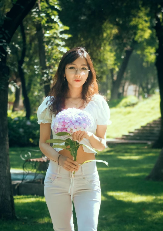 a woman with flowers stands in a park