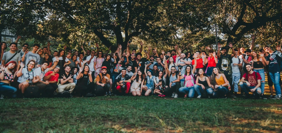 many people pose for a group pograph in front of some trees