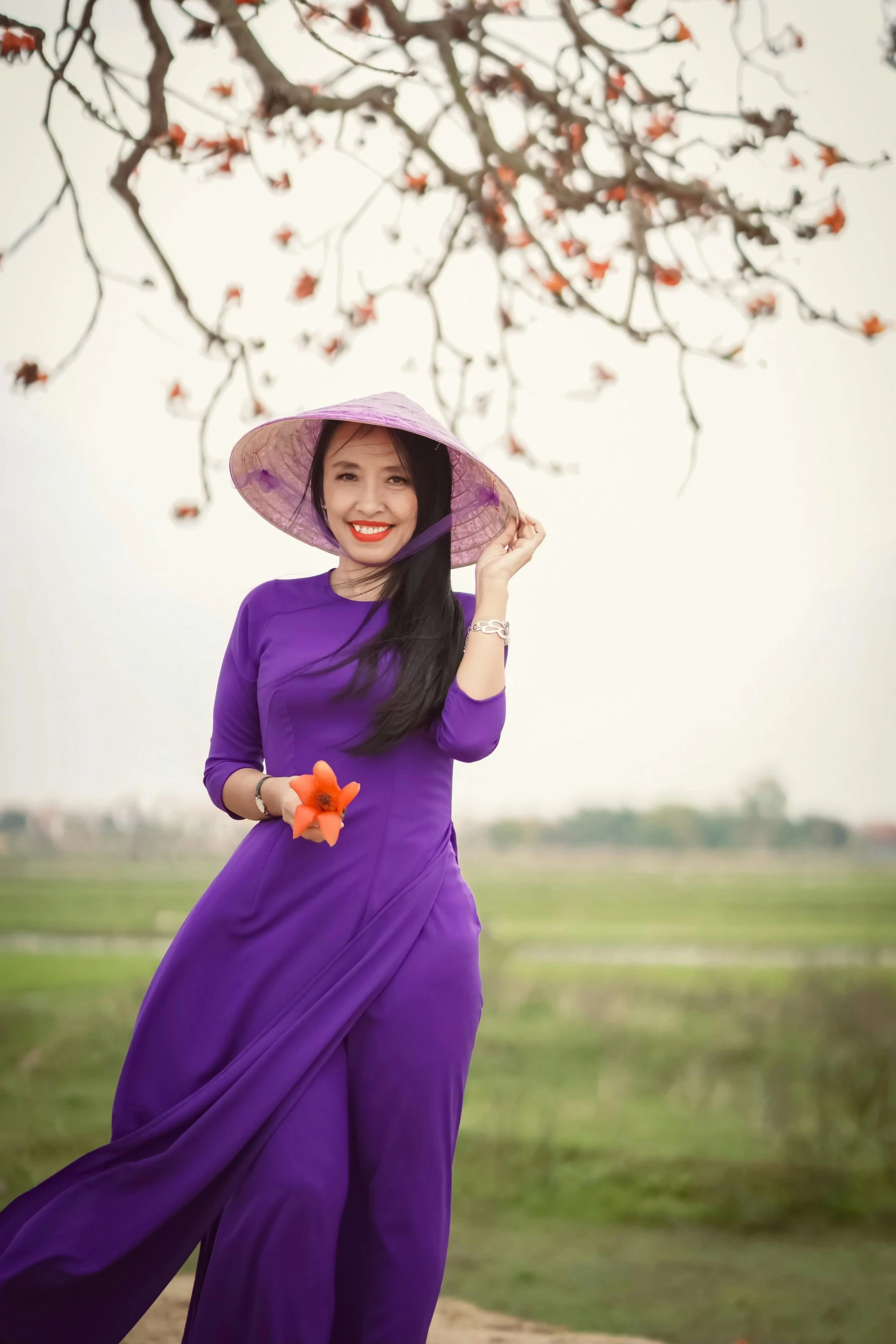 a woman wearing a purple dress and hat under a tree