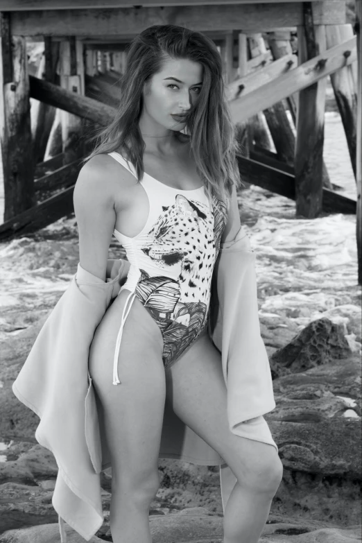 the model poses in her bathing suit by the water