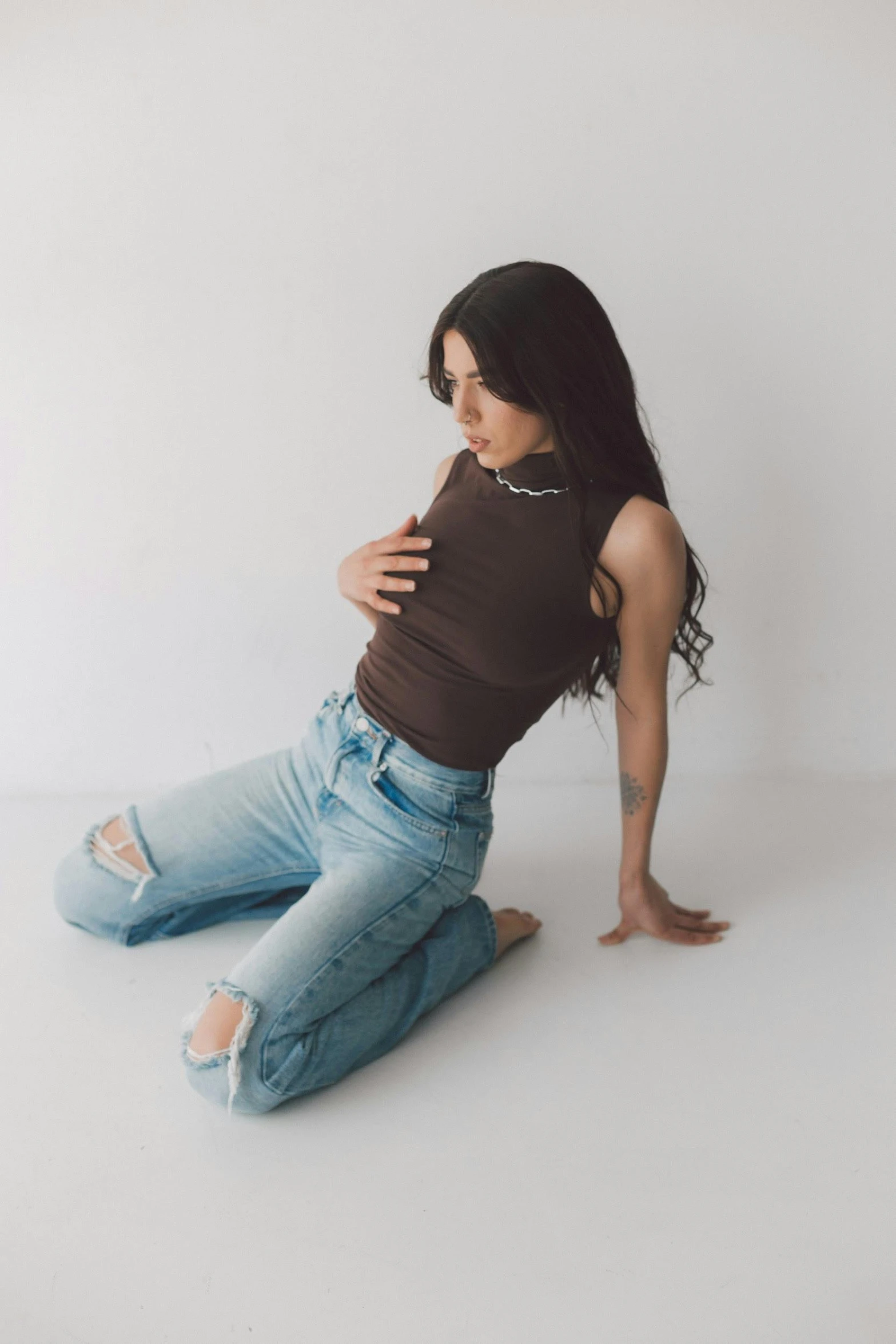 a woman with her arms crossed sitting down on the ground