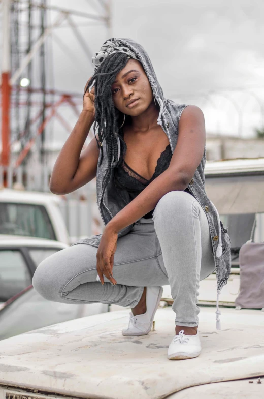 a black woman in grey clothes and white shoes on top of a white vehicle