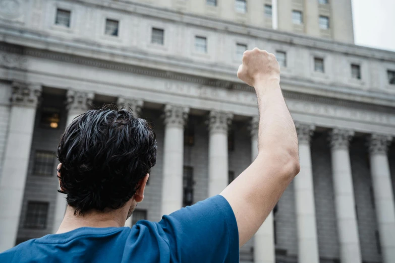 a man waving in front of a building with columns