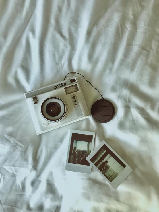 an old camera and polaroid sit on a bed