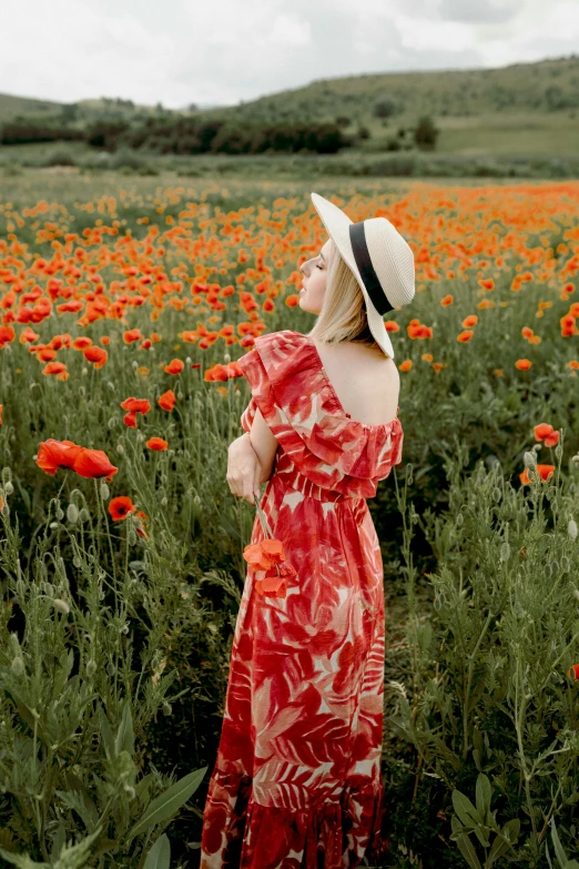 woman in hat in flowery field with orange flowers