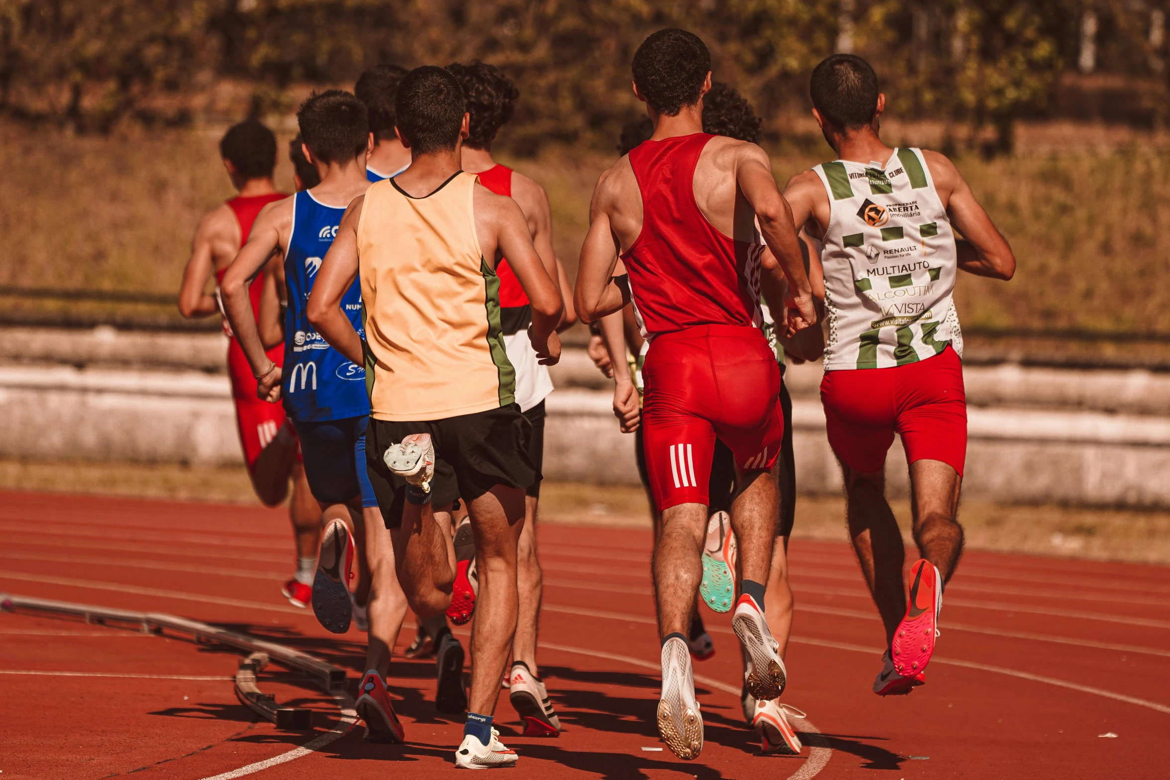 a group of young men running on top of a race track