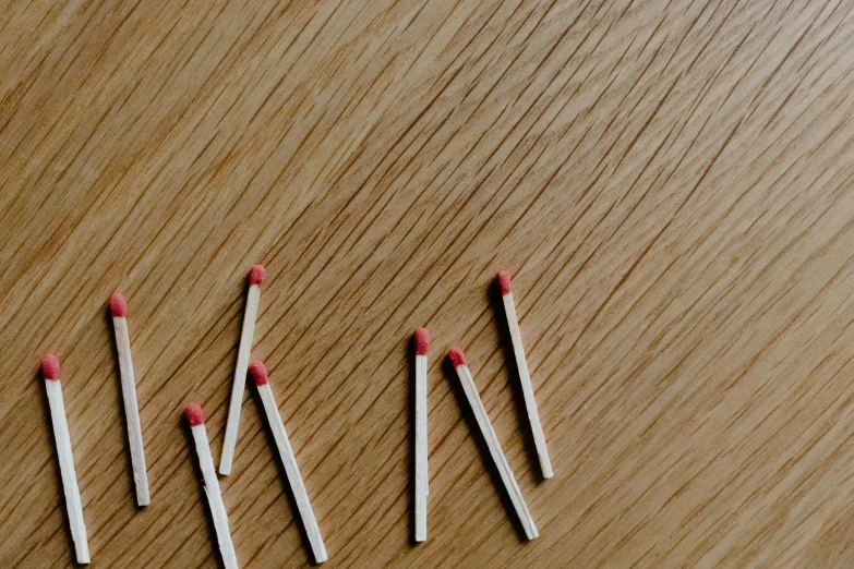 six matches in different stages lying on a wooden surface