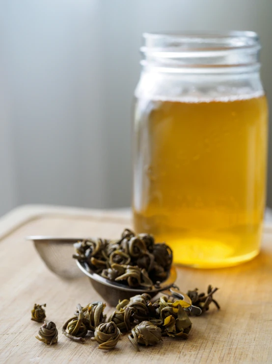 a spoon and some tea leaves near a jar