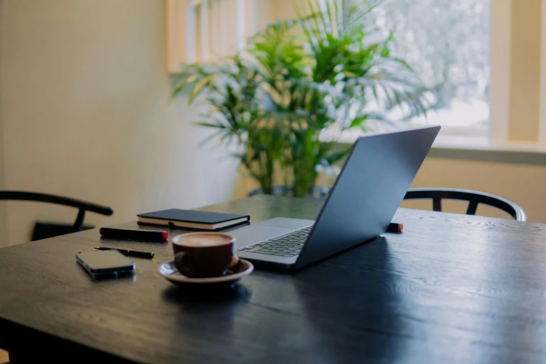 the laptop is sitting on the table next to the phone