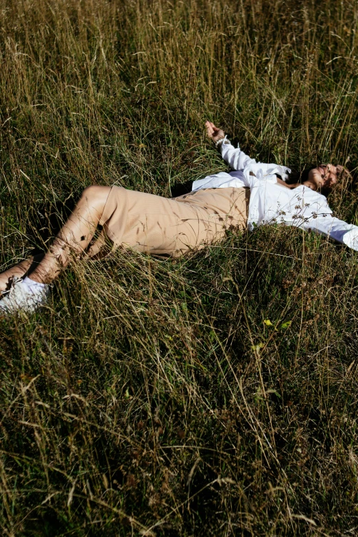 a man laying in the grass covered in grass