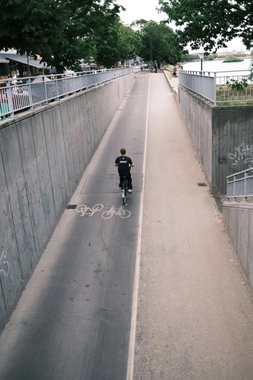 a man on a skateboard rides along a road with a graffiti covered fence