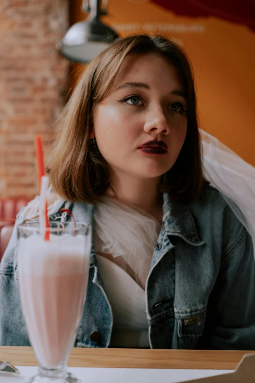 a woman sitting at a table with an ice cold drink in front of her