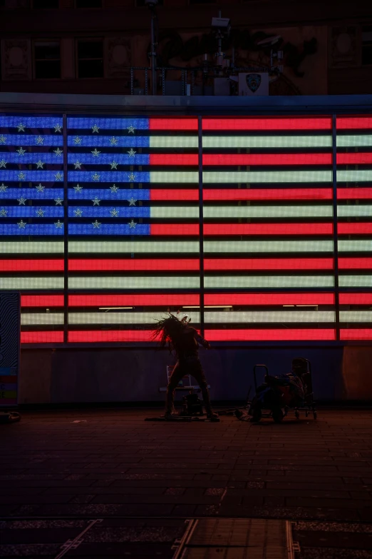 the red white and blue american flag lit in front of a building