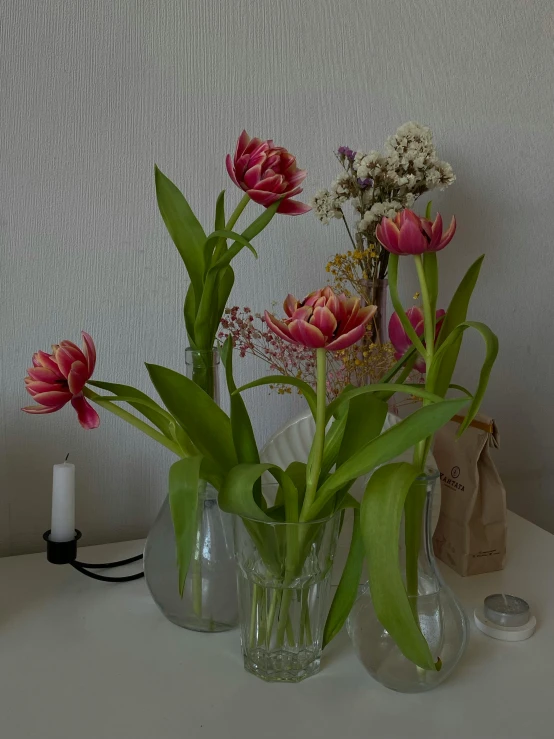 three vases filled with pink flowers on top of a table