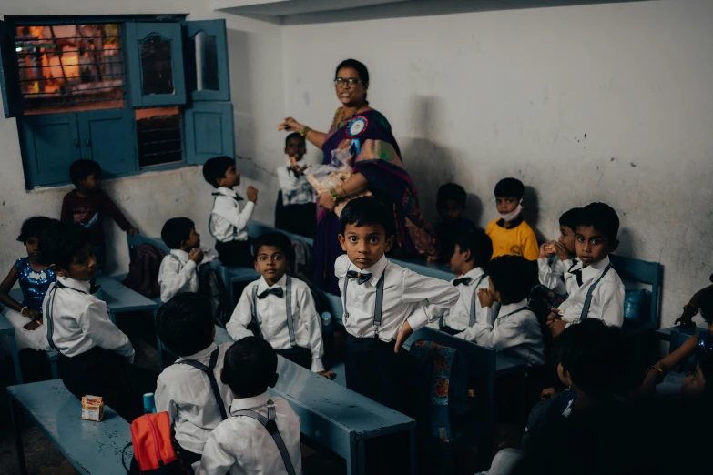 an adult standing behind two children in front of a classroom