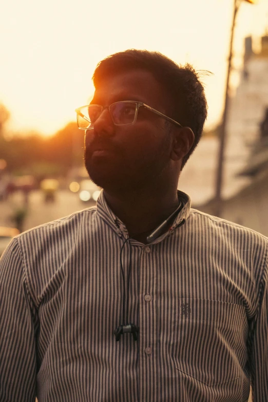 a man wearing glasses standing next to a street