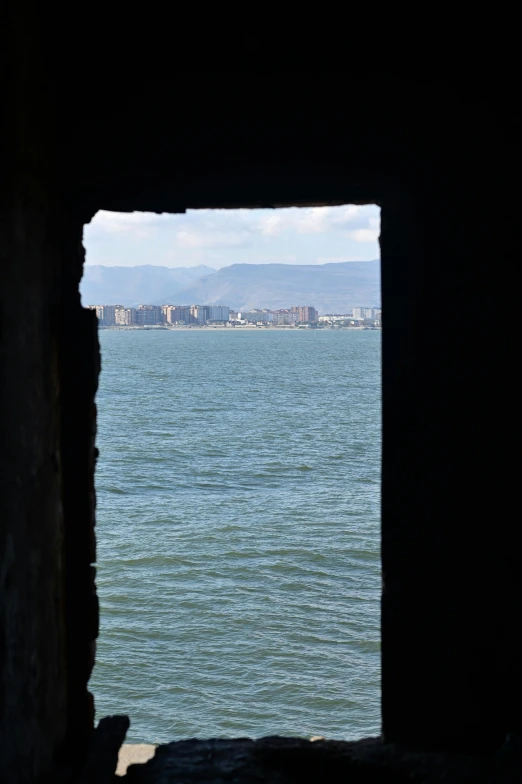 water inside an opening in a small wall with a city in the background