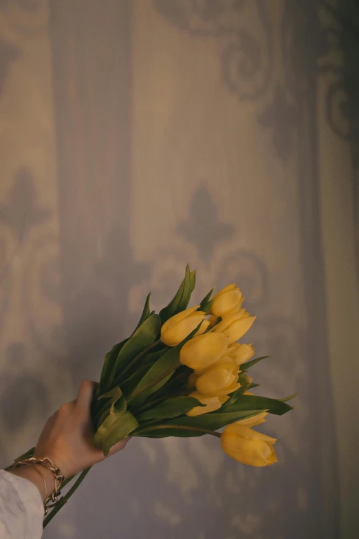 a person holding a bouquet of yellow flowers