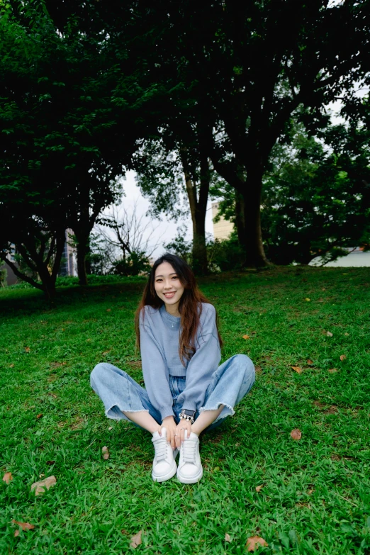 a woman sitting in a field with some trees