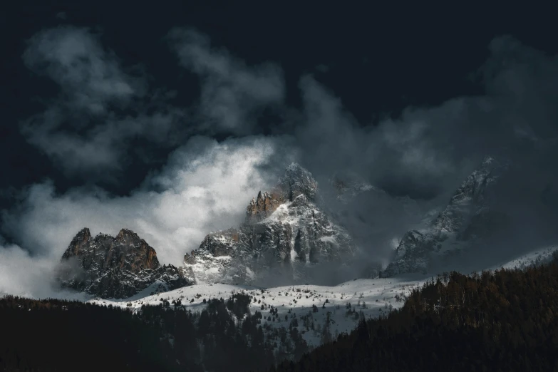 clouds move over a mountain range with pine trees