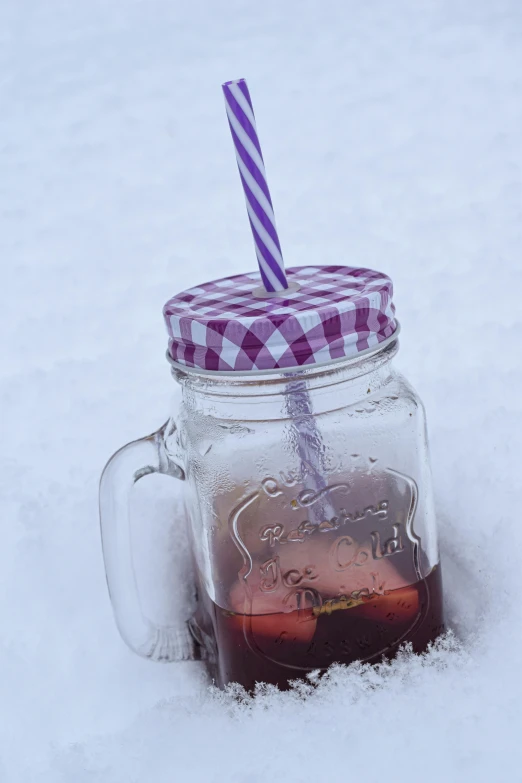 a jar is next to a bottle that has a purple and white straw on top