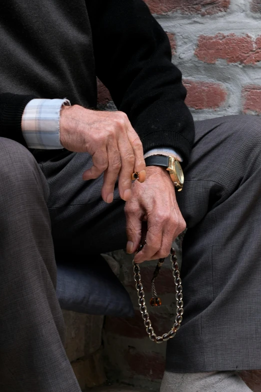 a man's hands sitting on a bench holding a handbag