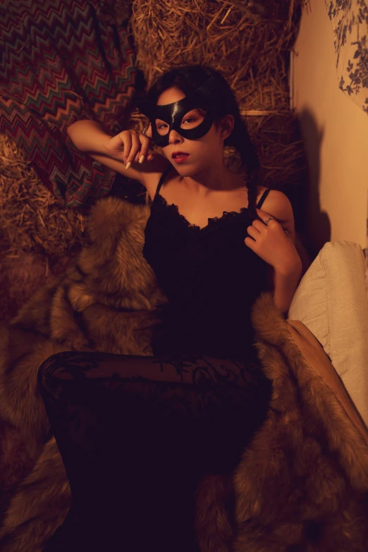 a woman with a mask and black lingerie poses on fur