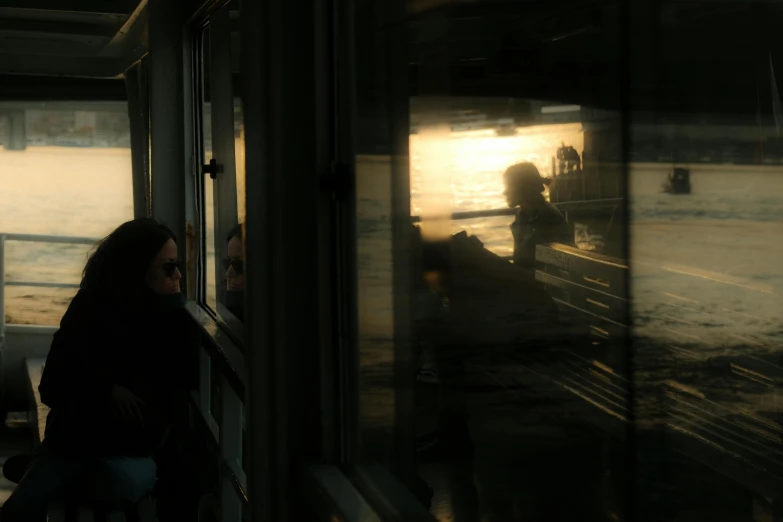 woman is looking out the window of a passenger train at sunset