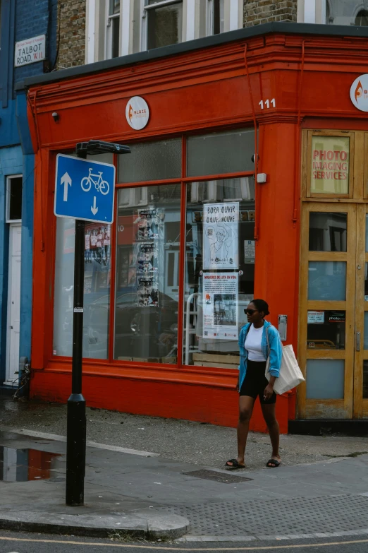 people walking down the street past buildings with signs