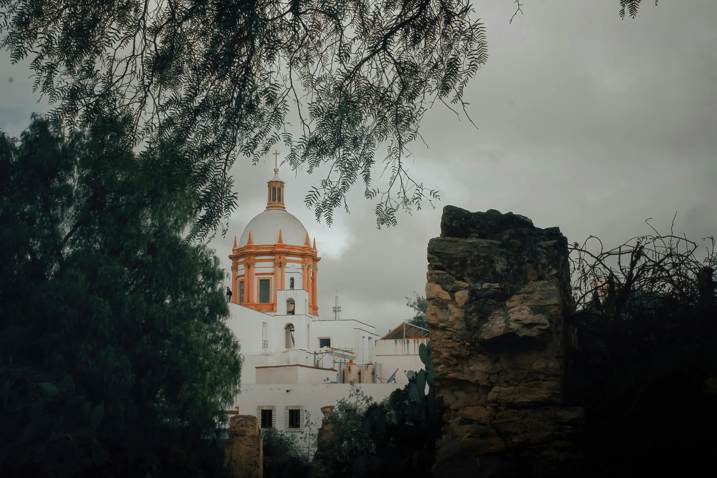 white and orange church on top of a mountain near trees