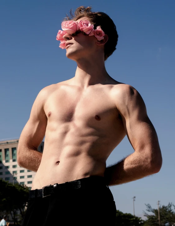 shirtless man with flower in the head standing on grass