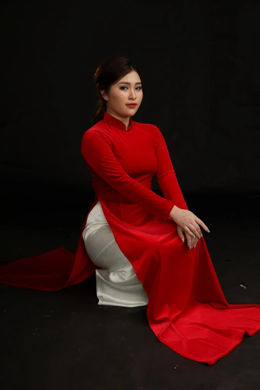 there is a woman in red sitting on a white stool