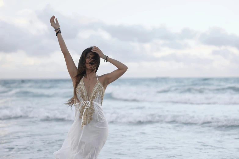 woman in white dress at beach with her hands up